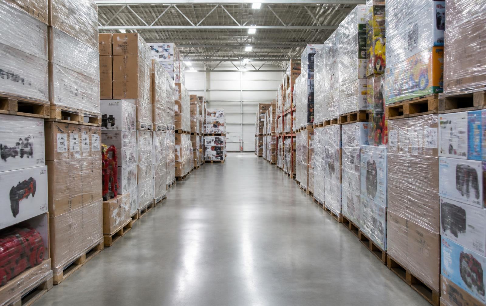 Warehouse aisle stacked with shrink-wrapped pallets of general merchandise